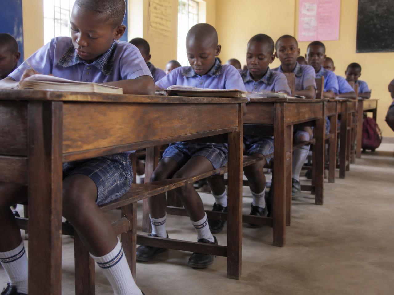 Nigerian primary school pupils seated at classroom desks wearing white knitted school socks